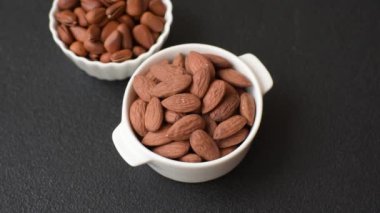 Koyu beton arka planda seramik kasede lezzetli, besleyici badem fıstıkları.