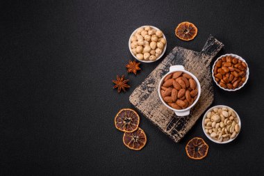 Koyu beton arka planda seramik kasede lezzetli, besleyici badem fıstıkları.