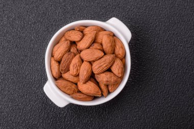 Koyu beton arka planda seramik kasede lezzetli, besleyici badem fıstıkları.