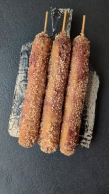 Lula kebabı ateşte kızartılmış, tuzlu, baharatlı ve otlu, koyu beton bir arka planda.