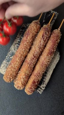 Lula kebabı ateşte kızartılmış, tuzlu, baharatlı ve otlu, koyu beton bir arka planda.