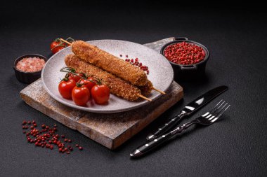 Lula kebabı ateşte kızartılmış, tuzlu, baharatlı ve otlu, koyu beton bir arka planda.