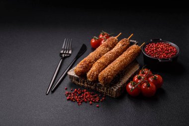 Lula kebabı ateşte kızartılmış, tuzlu, baharatlı ve otlu, koyu beton bir arka planda.