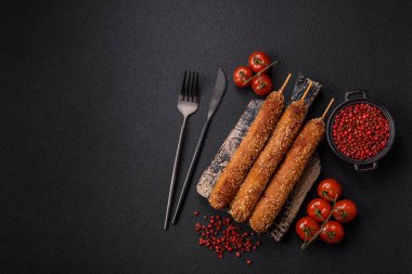 Lula kebabı ateşte kızartılmış, tuzlu, baharatlı ve otlu, koyu beton bir arka planda.