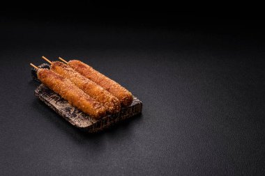 Lula kebabı ateşte kızartılmış, tuzlu, baharatlı ve otlu, koyu beton bir arka planda.