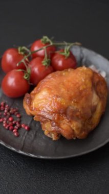 Tuz, baharat ve otlarla pişirilmiş lezzetli sulu tavuk butları koyu beton arka planda seramik bir tabakta.