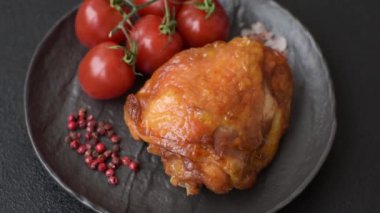 Tuz, baharat ve otlarla pişirilmiş lezzetli sulu tavuk butları koyu beton arka planda seramik bir tabakta.