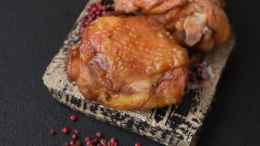 Tuz, baharat ve otlarla pişirilmiş lezzetli sulu tavuk butları koyu beton arka planda seramik bir tabakta.