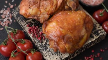 Tuz, baharat ve otlarla pişirilmiş lezzetli sulu tavuk butları koyu beton arka planda seramik bir tabakta.