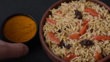 Lezzetli taze pilav, pirinç, havuç, et, soğan, baharat ve böğürtlen ile koyu beton arka planda seramik bir tabakta.