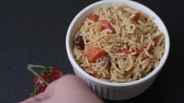 Lezzetli taze pilav, pirinç, havuç, et, soğan, baharat ve böğürtlen ile koyu beton arka planda seramik bir tabakta.