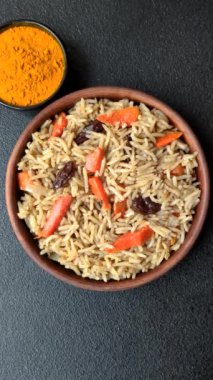 Lezzetli taze pilav, pirinç, havuç, et, soğan, baharat ve böğürtlen ile koyu beton arka planda seramik bir tabakta.