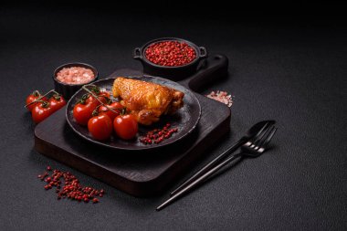 Tuz, baharat ve otlarla pişirilmiş lezzetli sulu tavuk butları koyu beton arka planda seramik bir tabakta.