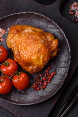 Tuz, baharat ve otlarla pişirilmiş lezzetli sulu tavuk butları koyu beton arka planda seramik bir tabakta.