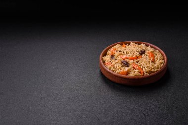 Lezzetli taze pilav, pirinç, havuç, et, soğan, baharat ve böğürtlen ile koyu beton arka planda seramik bir tabakta.