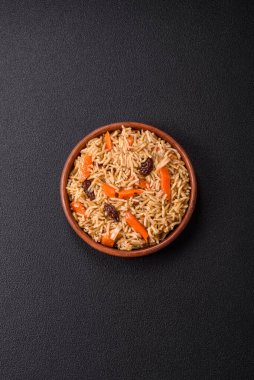 Lezzetli taze pilav, pirinç, havuç, et, soğan, baharat ve böğürtlen ile koyu beton arka planda seramik bir tabakta.