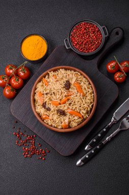 Lezzetli taze pilav, pirinç, havuç, et, soğan, baharat ve böğürtlen ile koyu beton arka planda seramik bir tabakta.