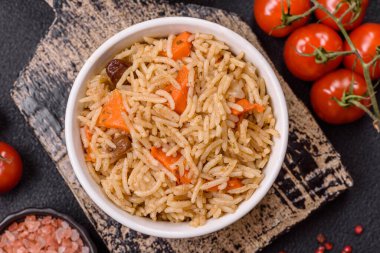 Lezzetli taze pilav, pirinç, havuç, et, soğan, baharat ve böğürtlen ile koyu beton arka planda seramik bir tabakta.