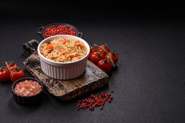 Lezzetli taze pilav, pirinç, havuç, et, soğan, baharat ve böğürtlen ile koyu beton arka planda seramik bir tabakta.