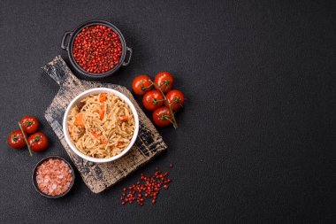 Lezzetli taze pilav, pirinç, havuç, et, soğan, baharat ve böğürtlen ile koyu beton arka planda seramik bir tabakta.