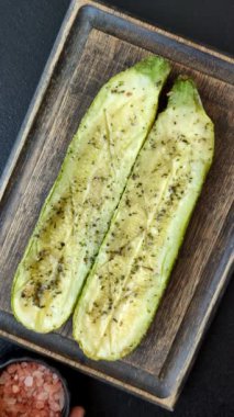 Tuz, baharat ve otlarla pişirilmiş, koyu beton arka planda iki parçaya bölünmüş lezzetli kabak.