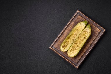 Tuz, baharat ve otlarla pişirilmiş, koyu beton arka planda iki parçaya bölünmüş lezzetli kabak.