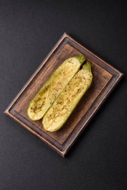 Tuz, baharat ve otlarla pişirilmiş, koyu beton arka planda iki parçaya bölünmüş lezzetli kabak.