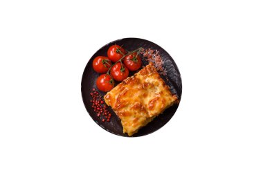 Beyaz arka planda et, peynir, tuz, baharat ve otlarla kaplı lazanya ya da makarna.