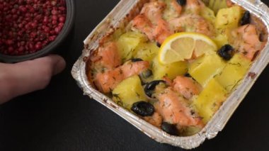 Fırında somon parçaları, patates, peynir ve tuzlu zeytinli, baharatlı ve çimento kaplı.