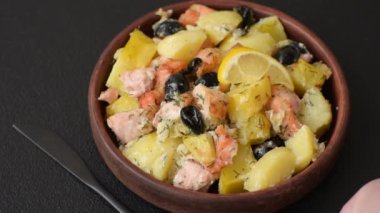 Fırında somon parçaları, patates, peynir ve tuzlu zeytinli, baharatlı ve çimento kaplı.