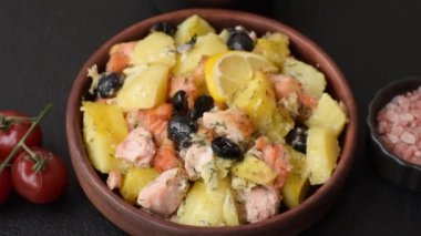 Fırında somon parçaları, patates, peynir ve tuzlu zeytinli, baharatlı ve çimento kaplı.