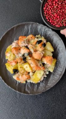 Fırında somon parçaları, patates, peynir ve tuzlu zeytinli, baharatlı ve çimento kaplı.