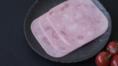 Tuzlu ve baharatlı haşlanmış jambon. Koyu beton arka planda dilimler halinde kesilmiş.