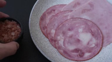 Tuzlu ve baharatlı haşlanmış jambon. Koyu beton arka planda dilimler halinde kesilmiş.