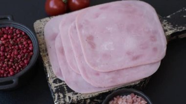 Tuzlu ve baharatlı haşlanmış jambon. Koyu beton arka planda dilimler halinde kesilmiş.