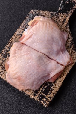 Taze çiğ tavuk butları, koyu beton arka planda tuz ve baharatlar.