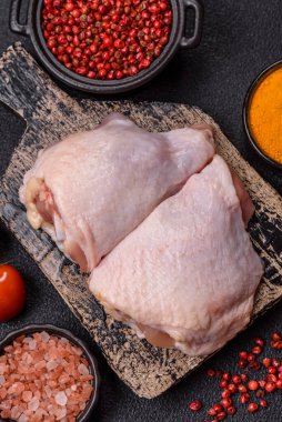 Taze çiğ tavuk butları, koyu beton arka planda tuz ve baharatlar.