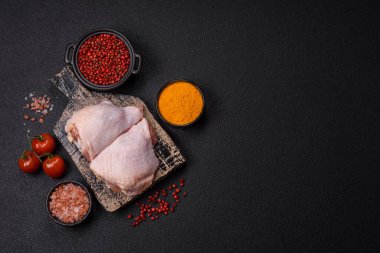 Taze çiğ tavuk butları, koyu beton arka planda tuz ve baharatlar.