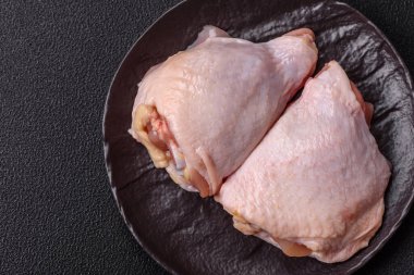 Taze çiğ tavuk butları, koyu beton arka planda tuz ve baharatlar.