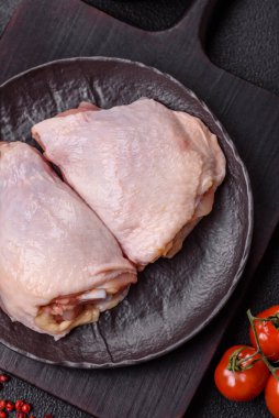 Taze çiğ tavuk butları, koyu beton arka planda tuz ve baharatlar.