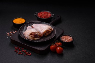 Taze çiğ tavuk butları, koyu beton arka planda tuz ve baharatlar.