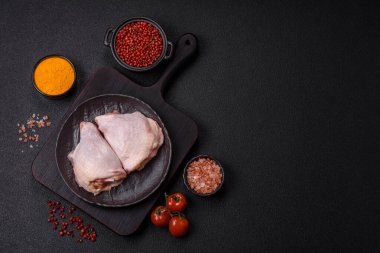 Taze çiğ tavuk butları, koyu beton arka planda tuz ve baharatlar.
