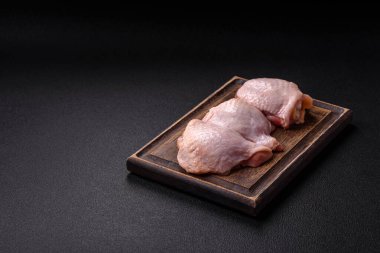 Taze çiğ tavuk butları, koyu beton arka planda tuz ve baharatlar.