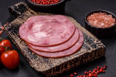 Tuzlu ve baharatlı haşlanmış jambon. Koyu beton arka planda dilimler halinde kesilmiş.