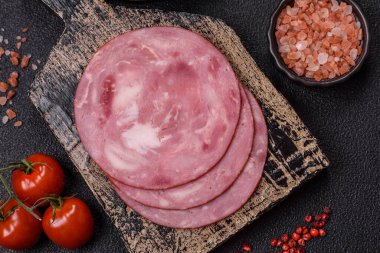 Tuzlu ve baharatlı haşlanmış jambon. Koyu beton arka planda dilimler halinde kesilmiş.