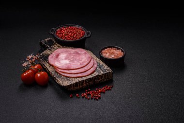 Tuzlu ve baharatlı haşlanmış jambon. Koyu beton arka planda dilimler halinde kesilmiş.