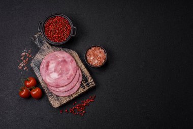 Tuzlu ve baharatlı haşlanmış jambon. Koyu beton arka planda dilimler halinde kesilmiş.