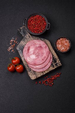 Tuzlu ve baharatlı haşlanmış jambon. Koyu beton arka planda dilimler halinde kesilmiş.