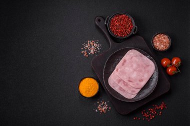 Tuzlu ve baharatlı haşlanmış jambon. Koyu beton arka planda dilimler halinde kesilmiş.