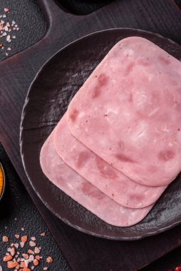 Tuzlu ve baharatlı haşlanmış jambon. Koyu beton arka planda dilimler halinde kesilmiş.